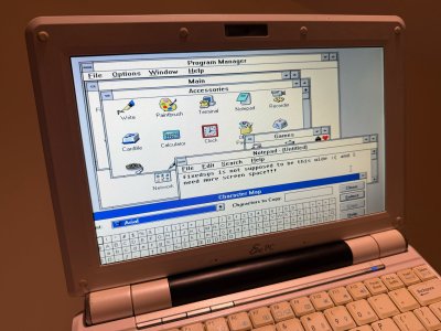 Windows 3.11 on my Eee PC, with a blurry and horizontally stretched screen. Text in Notepad says: "fixedsys is not supposed to be this wide :( and I need more screen space!!!"